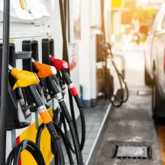 Zapfsäulen mit verschiedenen farbigen Zapfpistolen und einem Teil eines Autos im Hintergrund.