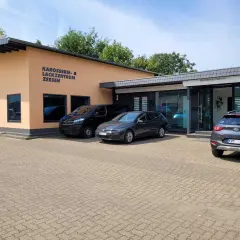 Gebäude des Karosserie- & Lackzentrums Zeesen mit Autos davor.
