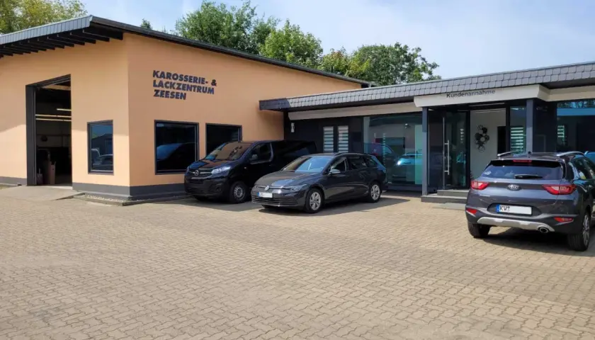 Gebäude des Karosserie- & Lackzentrums Zeesen mit Autos davor.